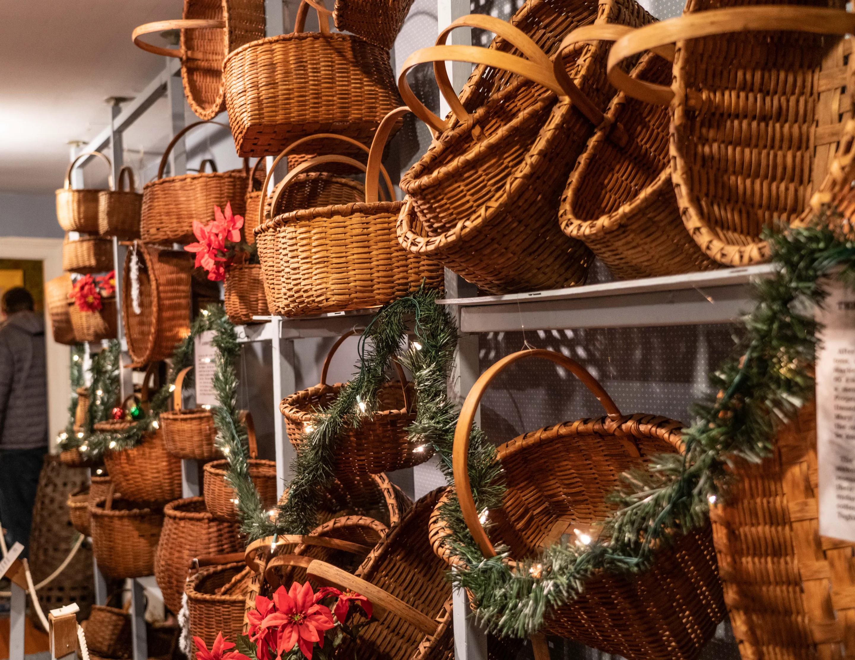The Boothe Homestead basket collection decorated with garland and poinsettias for Christmas
