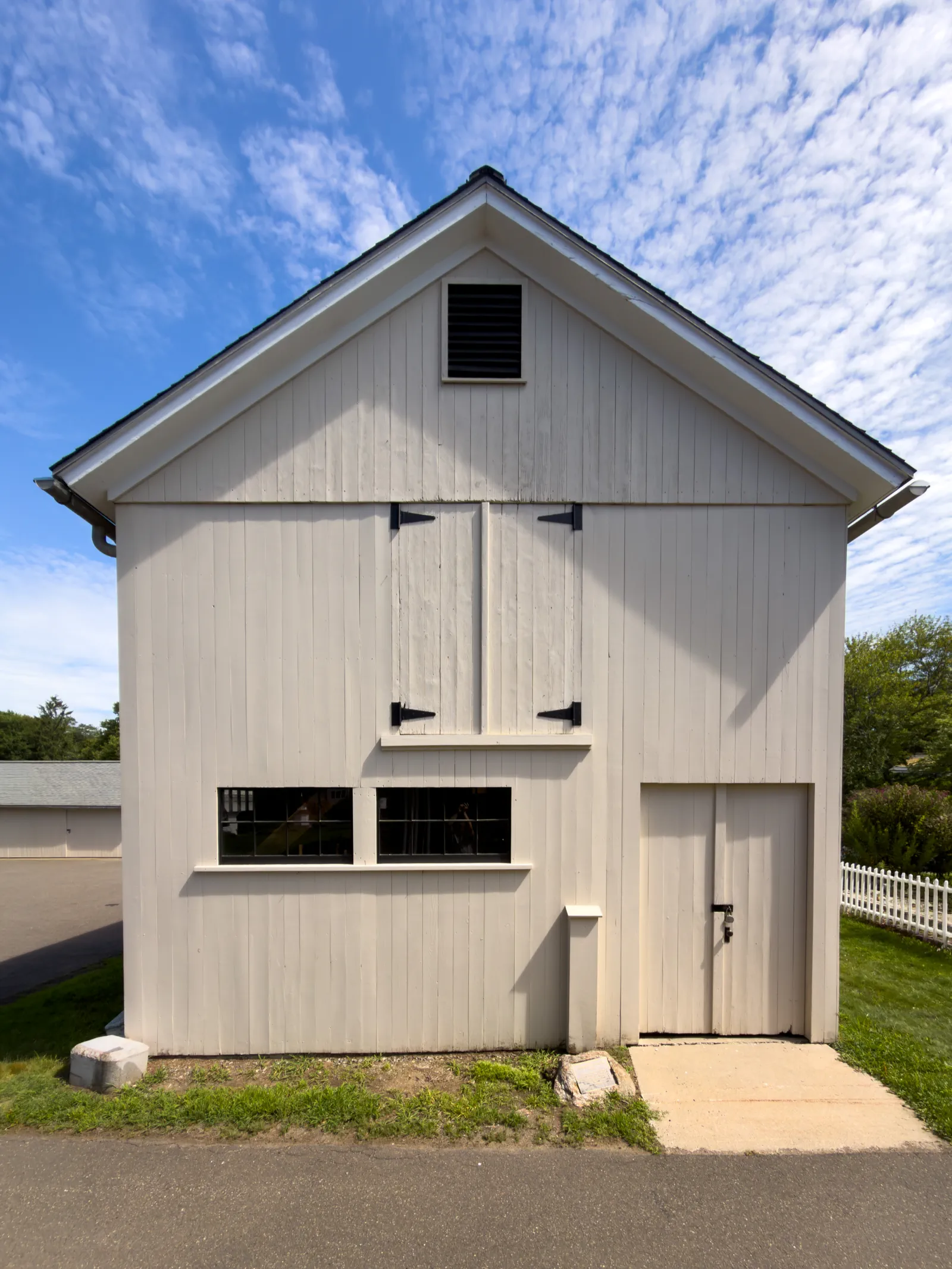 Front gable and barn doors of the white Americana Museum beneath a blue sky