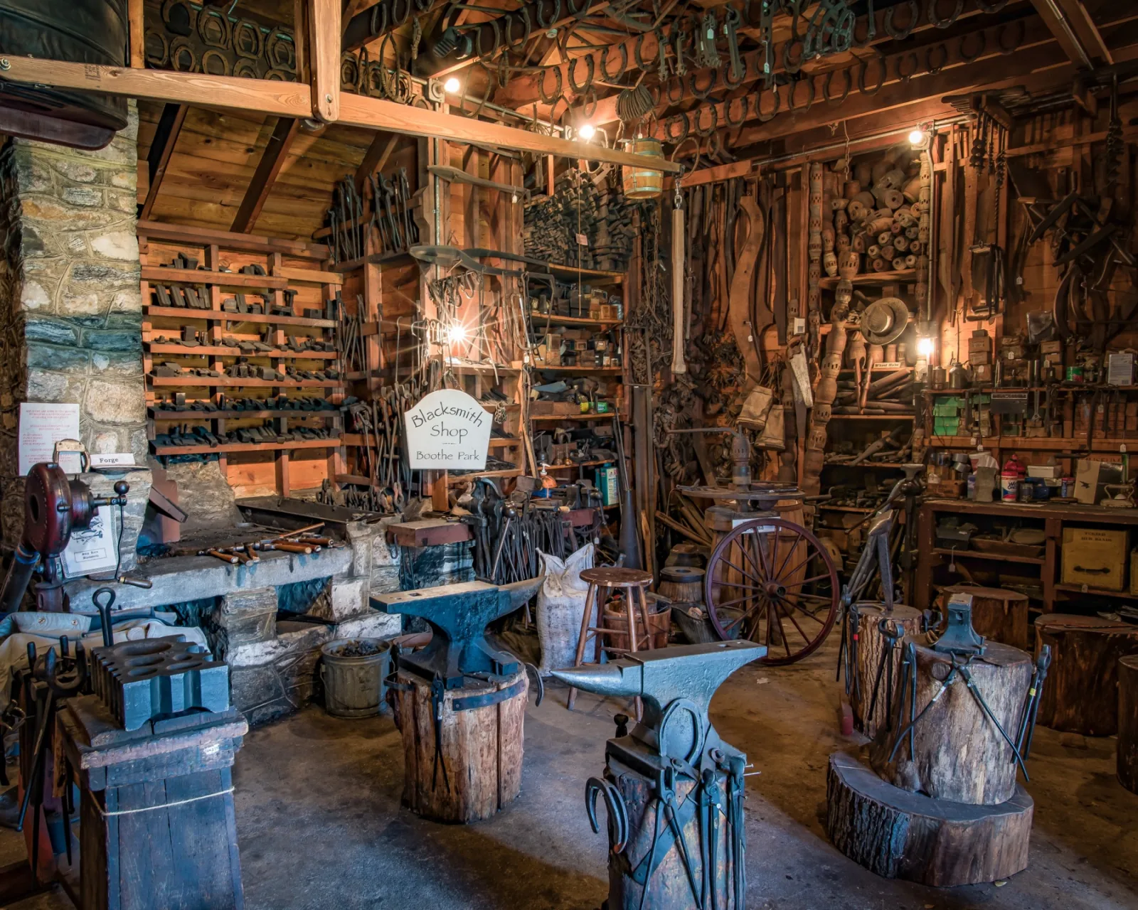 Wide interior view of tools, anvils, horseshoes, and workbenches inside the Boothe Park Blacksmith Shop
