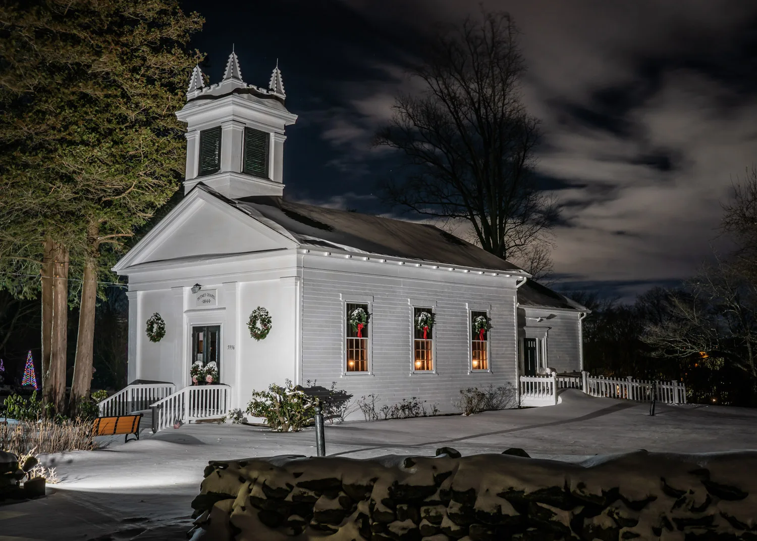 Putney Chapel illuminated on a winter night with snow on the ground and wreaths in the windows