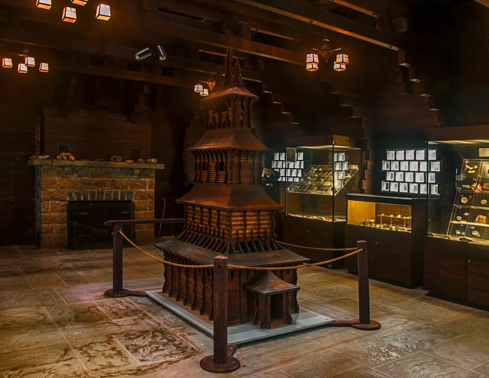 Scale model displayed between a stone fireplace and museum cases inside the Redwood Building