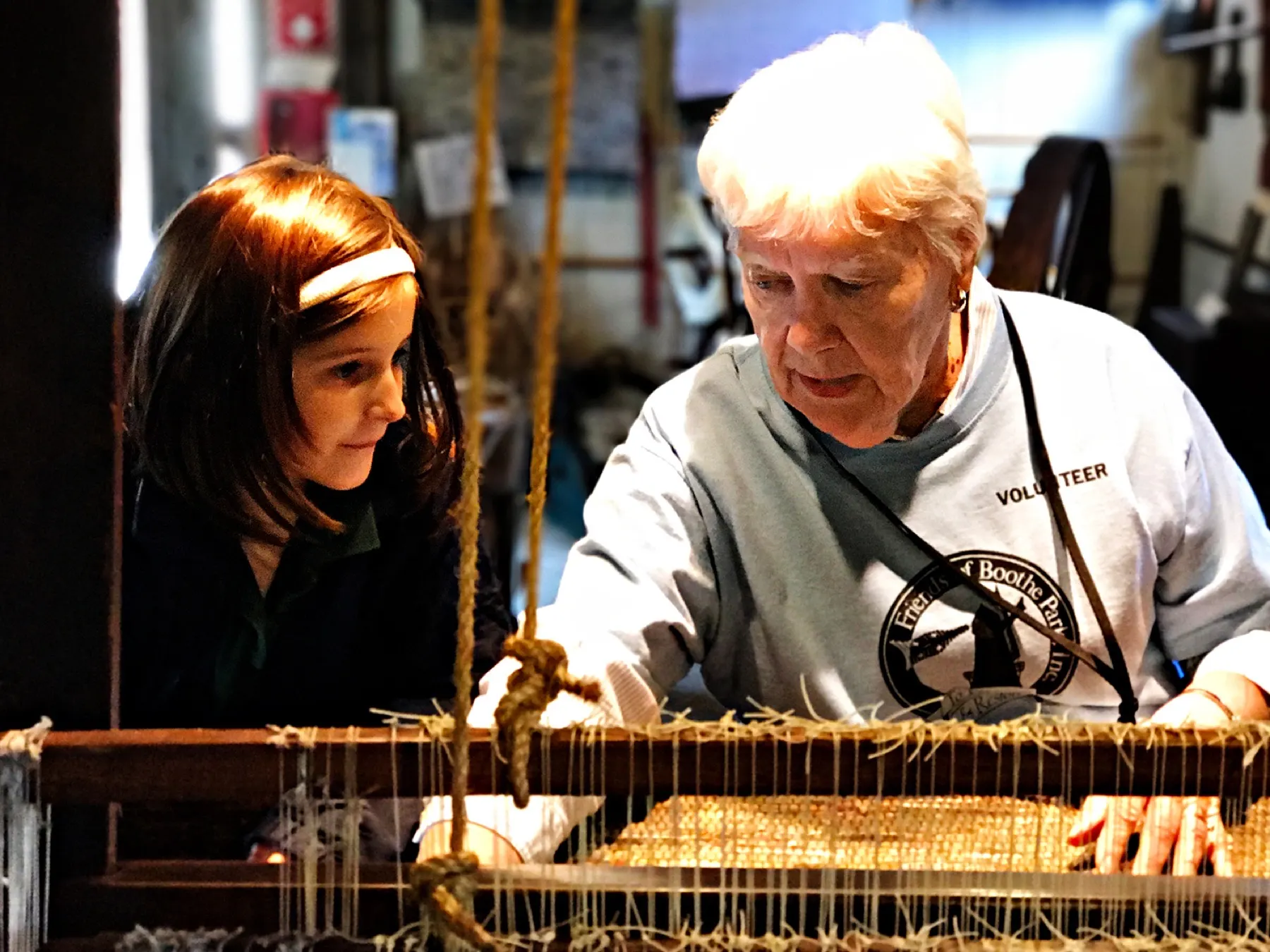 A Boothe Park volunteer showing a museum exhibit to a child